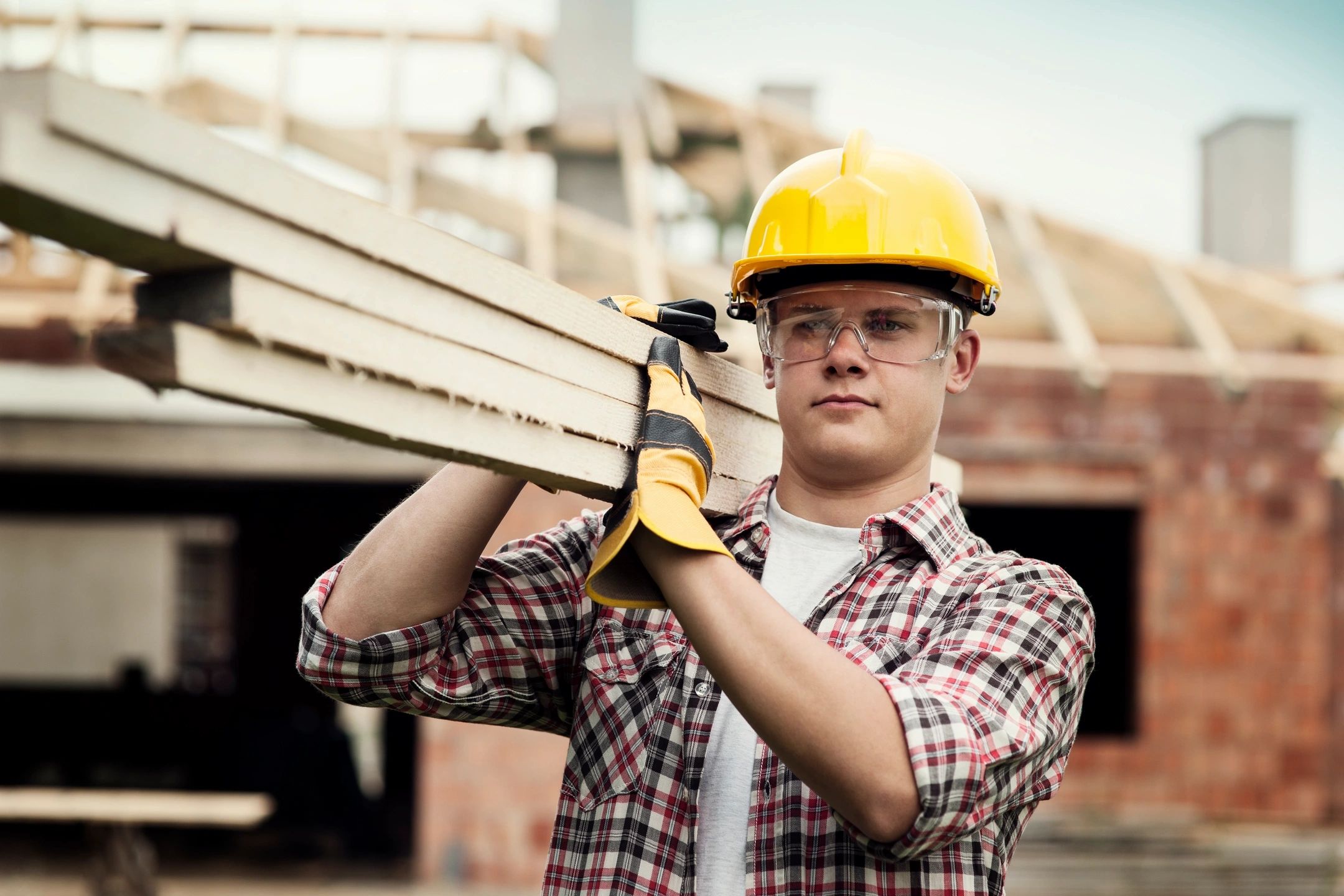 A construction worker in Staten Island is carrying a wooden pillars